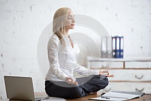 Businesswoman meditating in her office