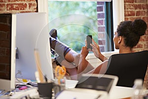 Businesswoman On Mobile Phone Relaxing In Modern Office