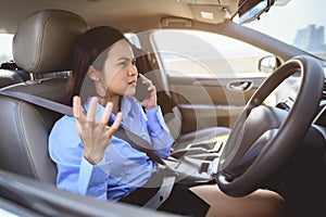 Businesswoman multitasking while driving car working and talking on cell phone on the road.