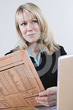 Businesswoman With Newspaper And Laptop