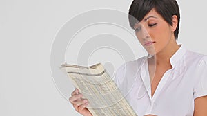 Businesswoman nods as she reads a newspaper