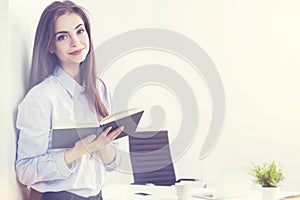 Businesswoman with notepad in sunlit office