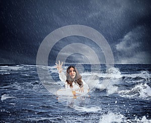 Businesswoman in the ocean with lifebelt asks help during a storm