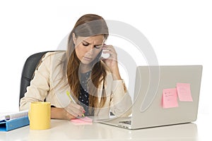 Businesswoman in at office computer desk talking on mobile phone taking notes