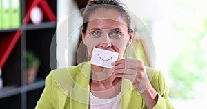 A businesswoman in an office with a fake smile on paper