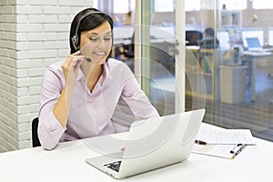 Businesswoman in the office on the phone with headset, Skype photo