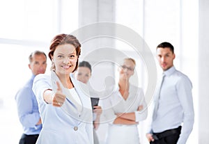 Businesswoman in office showing thumbs up