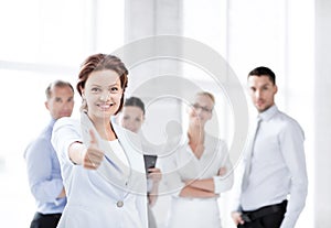 Businesswoman in office showing thumbs up