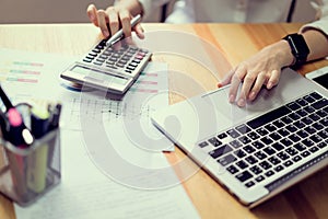 Businesswoman in office and use computer and calculator to perform financial accounting.