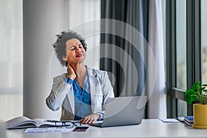Businesswoman office working holding sore neck pain from desk working and sitting all day using laptop computer or notebook