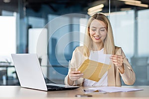 Businesswoman opening envelope with a happy expression