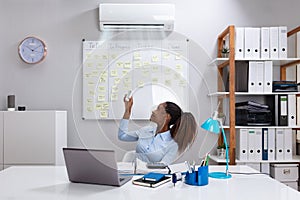 Businesswoman Operating Air Conditioner In Office