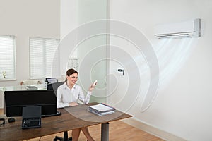 Businesswoman Operating Air Conditioner In Office