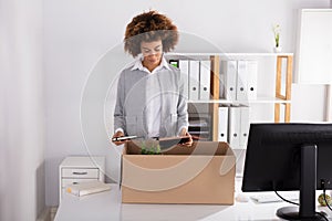 Businesswoman Packing Her Belongings In Cardboard Box