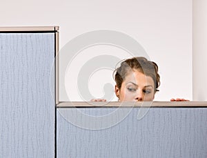Businesswoman peering over cubicle wall photo