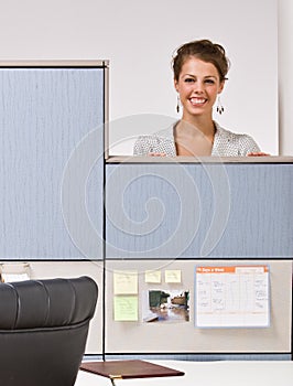 Businesswoman peering over cubicle wall photo