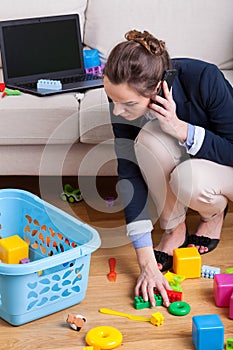 Businesswoman picking up toys