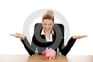 Businesswoman with a piggybank behind the desk