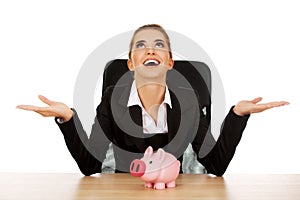 Businesswoman with a piggybank behind the desk