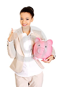 Businesswoman with piggybank and thumbs up.