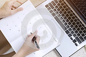 Businesswoman planning agenda and schedule using calendar event planner. Woman hands writing plan for working and schedule this