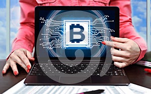 Businesswoman pointing on laptop screen with bitcoin sign on screen