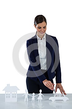 Businesswoman pointing on a paper cut out of family, car and house