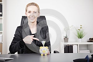 Businesswoman Pointing at Piggy Bank with Cash