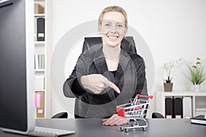 Businesswoman Pointing at Small Cart on her Desk