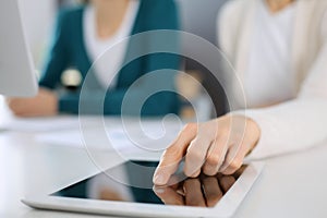 Businesswoman pointing at tablet computer screen while giving presentation to her female colleague. Group of business