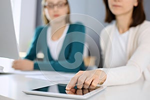 Businesswoman pointing at tablet computer screen while giving presentation to her female colleague. Group of business