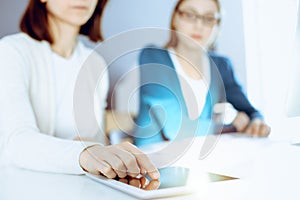 Businesswoman pointing at tablet computer screen while giving presentation to her female colleague. Group of business