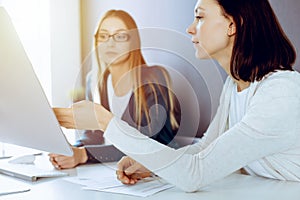 Businesswoman pointing at tablet computer screen while giving presentation to her female colleague. Group of business