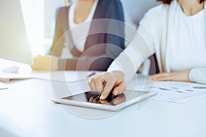 Businesswoman pointing at tablet computer screen while giving presentation to her female colleague. Group of business