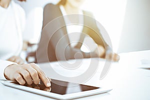 Businesswoman pointing at tablet computer screen while giving presentation to her female colleague. Group of business