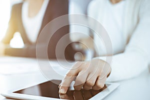 Businesswoman pointing at tablet computer screen while giving presentation to her female colleague. Group of business