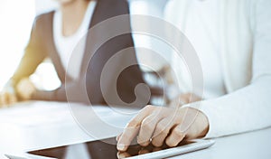 Businesswoman pointing at tablet computer screen while giving presentation to her female colleague. Group of business