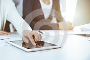 Businesswoman pointing at tablet computer screen while giving presentation to her female colleague. Group of business