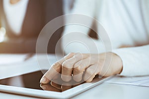 Businesswoman pointing at tablet computer screen while giving presentation to her female colleague. Group of business