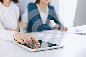 Businesswoman pointing at tablet computer screen while giving presentation to her female colleague. Group of business