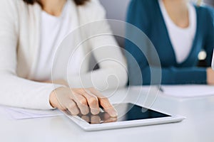 Businesswoman pointing at tablet computer screen while giving presentation to her female colleague. Group of business