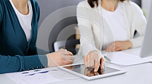 Businesswoman pointing at tablet computer screen while giving presentation to her female colleague. Group of business