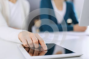 Businesswoman pointing at tablet computer screen while giving presentation to her female colleague. Group of business