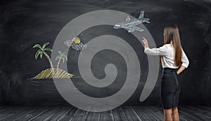 Businesswoman points a finger at sketch of plane and beach island on black background.