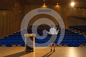 Businesswoman practicing and learning script while standing in the auditorium photo