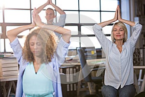 Businesswoman practicing yoga with colleagues