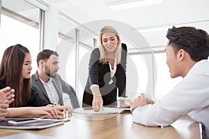 businesswoman presenting and pointing on the chart or document paper in meeting room . Group of young business people