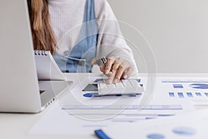 A businesswoman presses a calculator and looks at the data in the notebook.