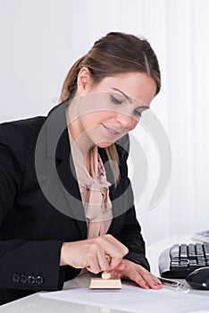 Businesswoman Pressing Wooden Stamp On Paper