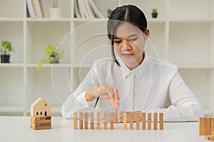 Businesswoman pulling or dropping wooden domino blocks. business risk management Solutions and Strategies in a modern office busin